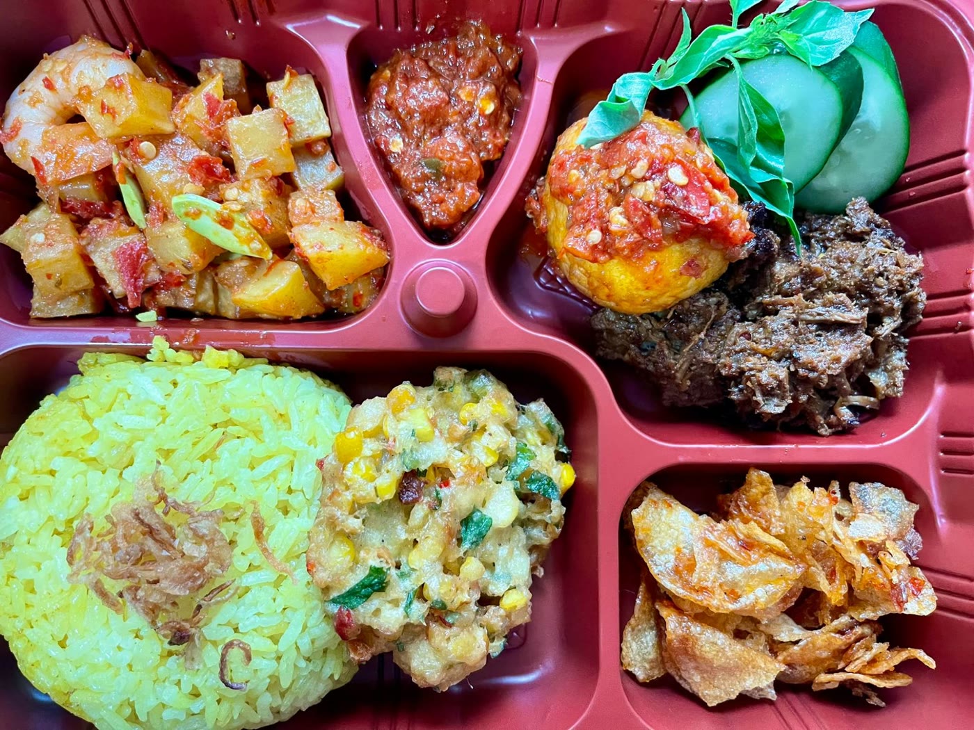 Set B bento: yellow rice, beef rendang, egg balado, sambal potato with prawn and petai, corn fritter, crispy sweet potato with peanuts and bilis, sambal