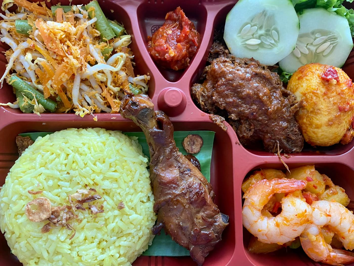 Set C bento: yellow rice, chicken kalasan drumstick, beef rendang, egg balado, sambal potato with prawn, urap, sambal